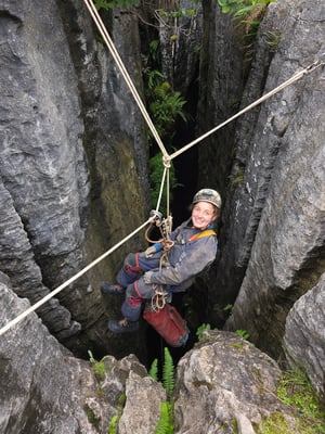 Caver at the top of a pothole, abseiling down a rope
