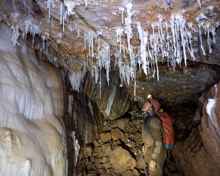 A caver looking at delicate formations in the White Forest