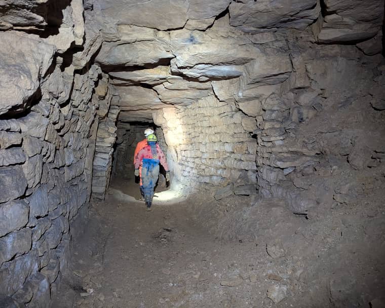 Two cavers walking through a passage in Windrush Stone Quarry